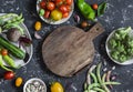 Food background. Assortment of fresh vegetables around the cutting board on a dark background. Top view Royalty Free Stock Photo