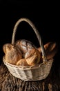 a basket with assortment of bread on wooden plank with dark background Royalty Free Stock Photo