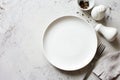 Food background- empty white plate, fork, napking,black peppers on gray stone slate