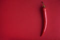 Food background flat lay. Red hot chili pepper on red background from above. Minimal creative still life with mexican spicy