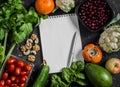 Food background. Fresh vegetables, fruits and blank notepad on a dark background. Concept of healthy eating