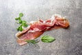 Food background with ham jamon serrano and herbs - rosemary, basil and watercress salad, stone gray background, top view Royalty Free Stock Photo