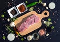 Food background. Meat on a cutting board and pepper, bay leaf, rosemary, onions, Himalayan salt, olive oil, soy sauce on a black Royalty Free Stock Photo