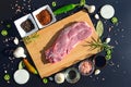 Food background. Meat on a cutting board and pepper, bay leaf, rosemary, onions, Himalayan salt, olive oil, soy sauce on a black