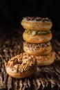 A piece of donut on wooden plank with a stack of donuts behind on dark background