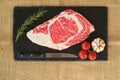 Aw fresh beef ribeye steak with rosemary on black stone plate Royalty Free Stock Photo