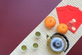 Food background set with tea, cups and pot, red packet and fresh orange on white bamboo mat. Royalty Free Stock Photo