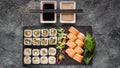 Food banner: set of different rolls on a black stone cutting board. Rolls with salmon, vegetables sushi maki rolls and fresh salad Royalty Free Stock Photo