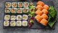 Food banner: set of different rolls on a black stone cutting board. Rolls with salmon, vegetables sushi maki rolls and fresh salad Royalty Free Stock Photo