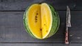 Food banner. Yellow watermelon and knife on a dark wooden background. Top view Royalty Free Stock Photo