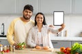 Positive young indian couple cooking at home, showing digital tablet Royalty Free Stock Photo