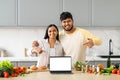 Positive young indian couple cooking at home, showing laptop Royalty Free Stock Photo