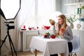 Food blogger cooking fresh vegan salad of fruits in kitchen studio, filming tutorial on camera for video channel. Female Royalty Free Stock Photo