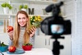 Food blogger cooking fresh vegan salad of fruits in kitchen studio, filming tutorial on camera for video channel. Female Royalty Free Stock Photo