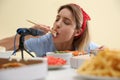 Food blogger eating in front of microphone at table against light background. Mukbang vlog