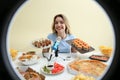 Food blogger eating at table against beige, view through ring light. Mukbang vlog