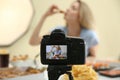 Food blogger recording eating show against light background, focus on camera screen. Mukbang vlog Royalty Free Stock Photo