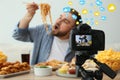 Food blogger recording eating show against light background, focus on camera screen. Mukbang vlog Royalty Free Stock Photo