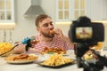 Food blogger recording eating show on camera in kitchen Royalty Free Stock Photo
