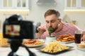 Food blogger recording eating show on camera in kitchen Royalty Free Stock Photo