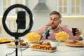 Food blogger recording eating show on smartphone camera in kitchen. Mukbang vlog Royalty Free Stock Photo