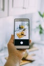 Food blogger takes photo on smartphone for social networks. Female hand holding cell phone with photo of cooking process Royalty Free Stock Photo