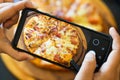 Food blogger taking picture of cooked pizza. Woman& x27;s hands with smartphone takes picture of fresh baked hot selfmade pizza. Royalty Free Stock Photo