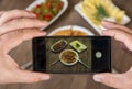 Food blogger using smartphone taking photo .Mans hands make phone photography of traditional meals. Royalty Free Stock Photo