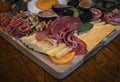 Food board with cured meats prosciutto, salami and coppa, brie, cheddar and other cheeses and fruits decorated with sage