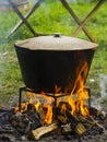 Food in a cauldron on a fire. Cooking outdoors in cast-iron cauldron.