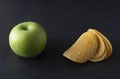 Food choise concept. Potatoe chips or green apple for snack. Top view, black background