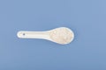 Food coloring, E171. White chemical powder in ceramic spoon on blue background, top view. Titanium dioxide, TiO2. Pigment present