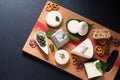 Food concept assortment French organic fresh goat cheese on wooden cheese board on black background with copy space