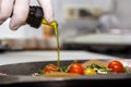 Food concept. Chef is pouring olive oil over fresh salad in restaurant kitchen Royalty Free Stock Photo