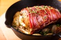 Food concept homemade Bacon Stuffed Pork Tenderloin baked in iron cast skillet on round wooden board