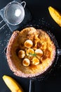 Food concept Homemade Dutch baby banana caramel topping pancake in skillet iron cast on black background