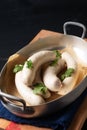 Food concept homemade organic German white sausage Weisswurst in aluminum tray on black slate stone with copy space