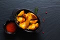 Food concept homemade organic Seasoned Baked Potato wedges in black bowl on black slate stone plate with copy space