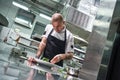 Food concept. Portrait of handsome professional chef in black apron decorating a salad on the plate while working in Royalty Free Stock Photo