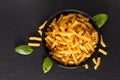 Food concept raw organic Italian Fusili pasta in black bowl on black slate board with copy space