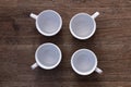 Food concept - top view of four white cups without saucers on gray brown wood table. Empty ceramic mugs. Royalty Free Stock Photo