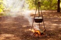Food is cooked on campfire in forest. Traveling, tourism, picnic cooking in cauldron, fire