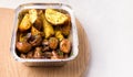 Food Delivery Concept. Fried potatoes with mushrooms in a container on a white background. Copy space.