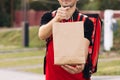 Food delivery man order from a restaurant. Handsome young man in a T-shirt and a cap. Happy delivery worker holding Royalty Free Stock Photo