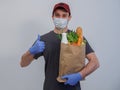 Food delivery man with a package of fresh vegetables, herbs, milk, bread in a mask and gloves to protect against COVID Royalty Free Stock Photo