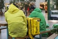 Food delivery men with thermal bags in uniforms sit on a bench with smartphones in their hands. Coronavirus pandemic. Moscow,