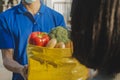 Food delivery service man in blue uniform wearing protection face mask holding fresh food set bag to customer Royalty Free Stock Photo