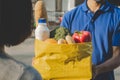 Food delivery service man with protection face mask in blue uniform holding fresh food set bag to customer Royalty Free Stock Photo