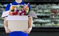 Food delivery service for order online grocery shopping concept. Delivery man in blue uniform hand holding paper box package. Royalty Free Stock Photo