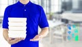 Food delivery service or order food online. Delivery man hand holding fast food packaging in blue uniform and icon symbol media on Royalty Free Stock Photo